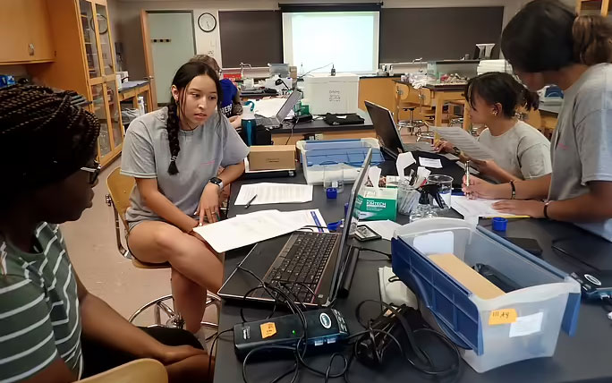 A lab classroom with students working together around a table.