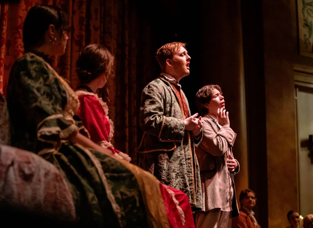 A theatrical scene shows several performers onstage