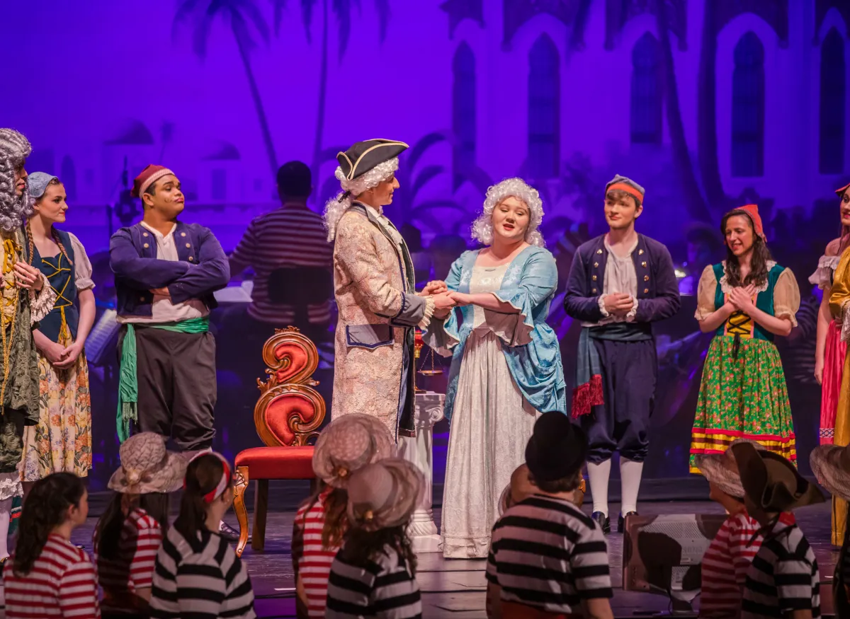 A theatrical scene shows several performers onstage