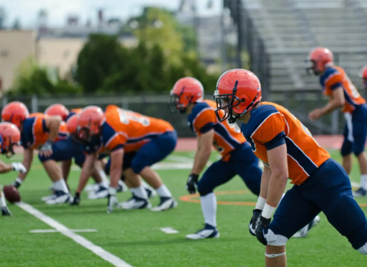 Gettysburg football players line up on a turf field before a play.