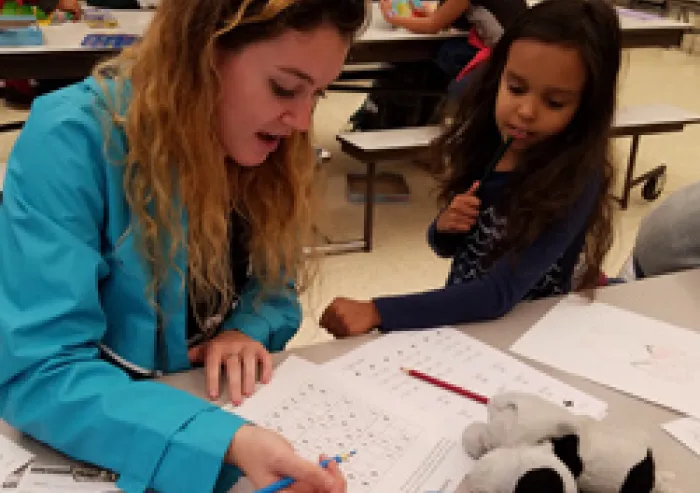 A student teaching a small child.