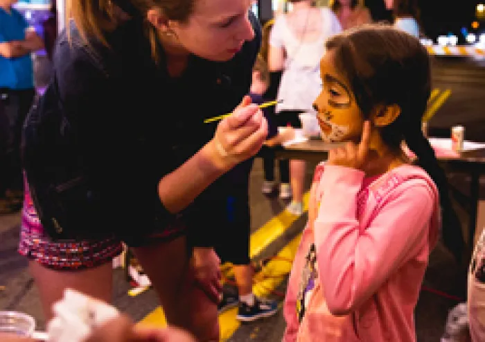 A student paints a young child's face.