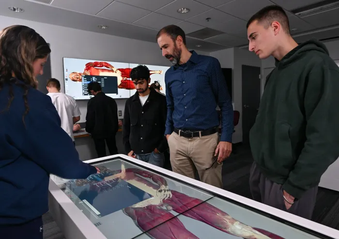 A professor and students looking at the anatomage table.