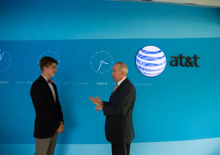 Student speaks with an AT&T executive in front of a global clocks display.