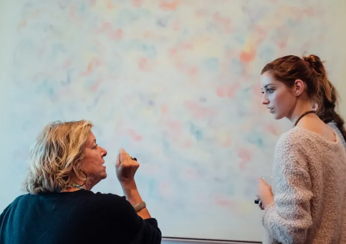 Two people discuss ideas beside a whiteboard.