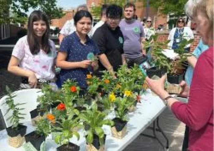 A group of students standing around a table with plants on it.