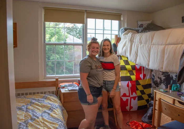 Two students stand in their dorm room.
