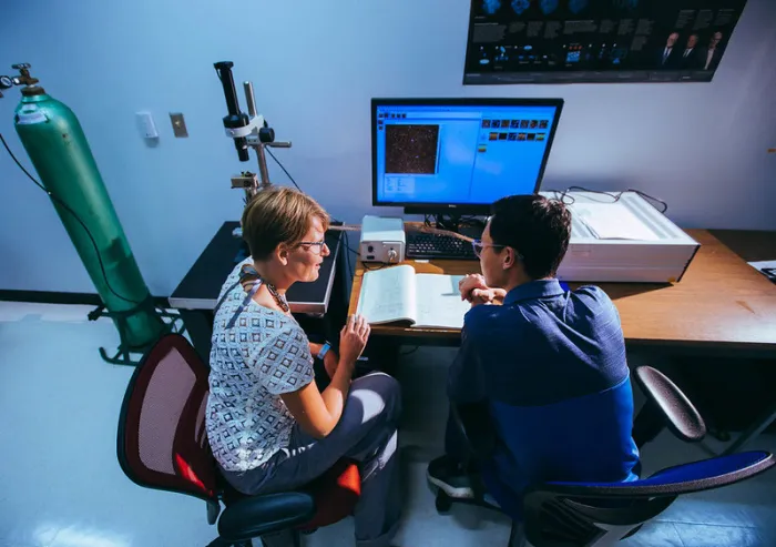 A teacher and student work at a computer.