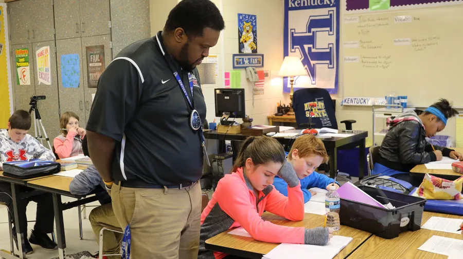 teacher watches young students at work in classroom