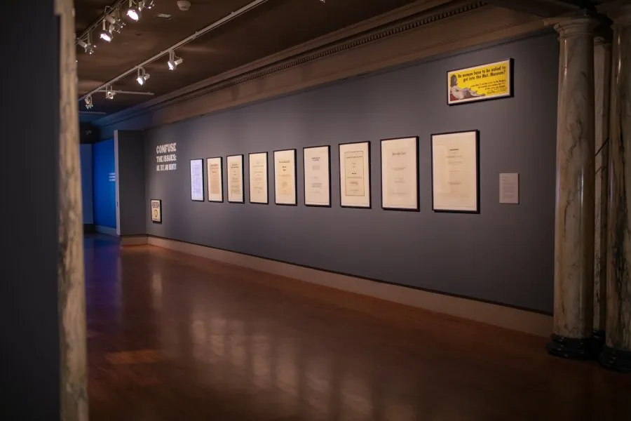 blue gallery wall with framed white posters mounted in a row