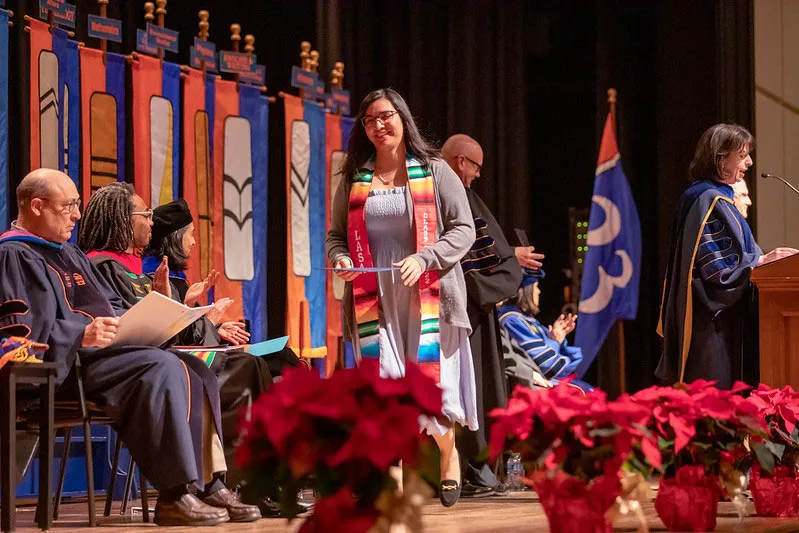 Graduate walking across stage with her diploma