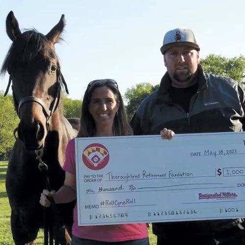 photo of author of roll Cyrus Roll standing with Cyrus handing oversized check for $1000 to thoroughbred retirement foundation