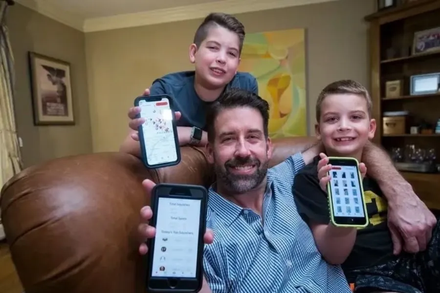 dad and two sons hold up phones