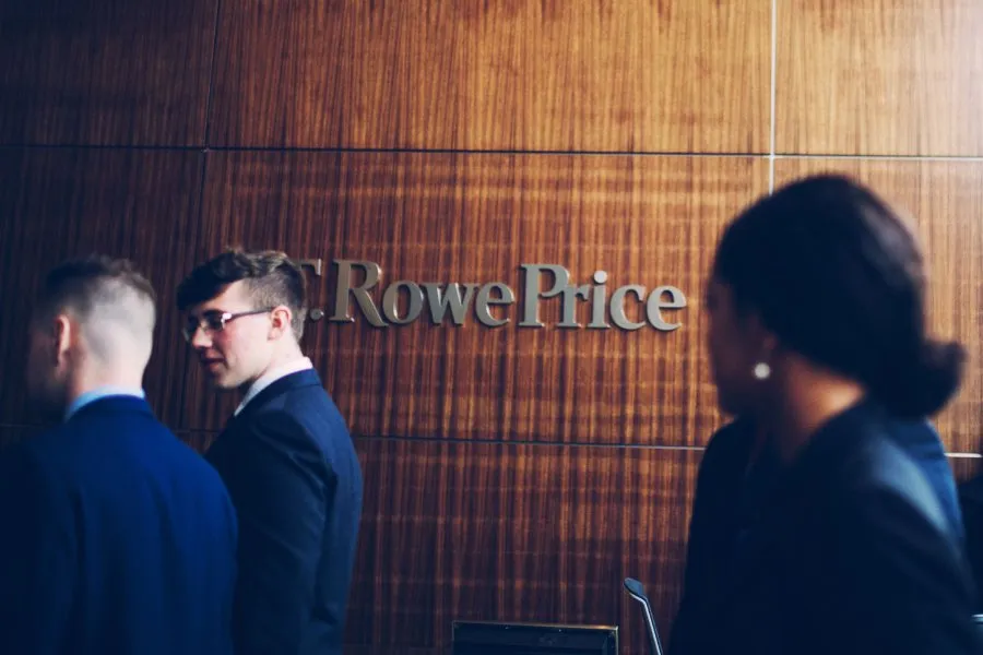 students walk in front of wall branded with T. Rowe Price