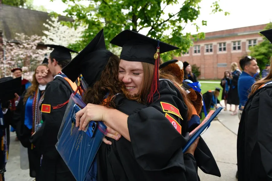 grads hug at Commencement