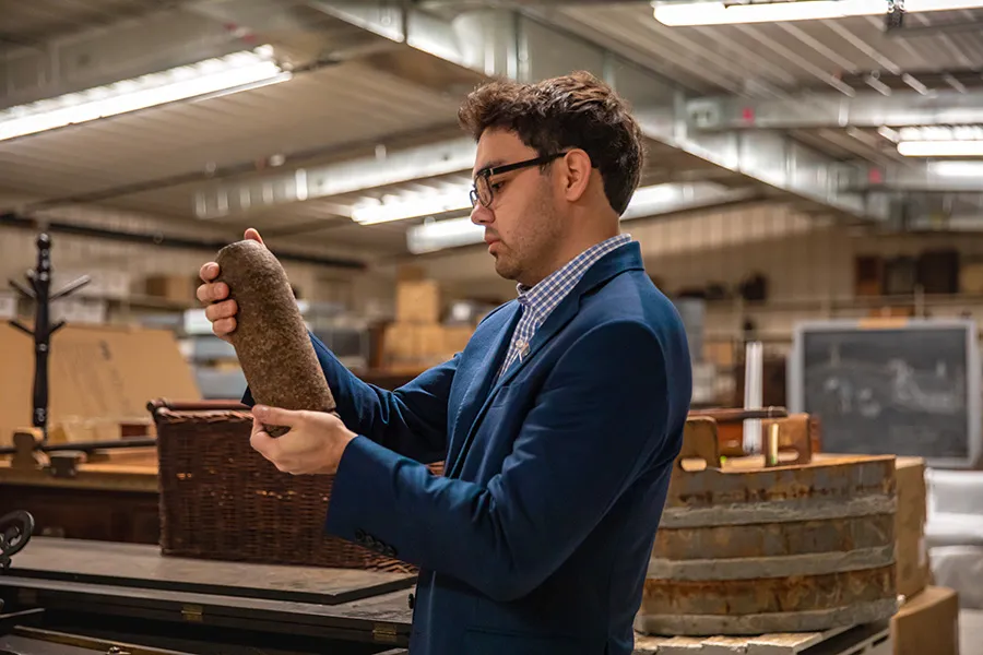 male alum examines historical artifact in archives room