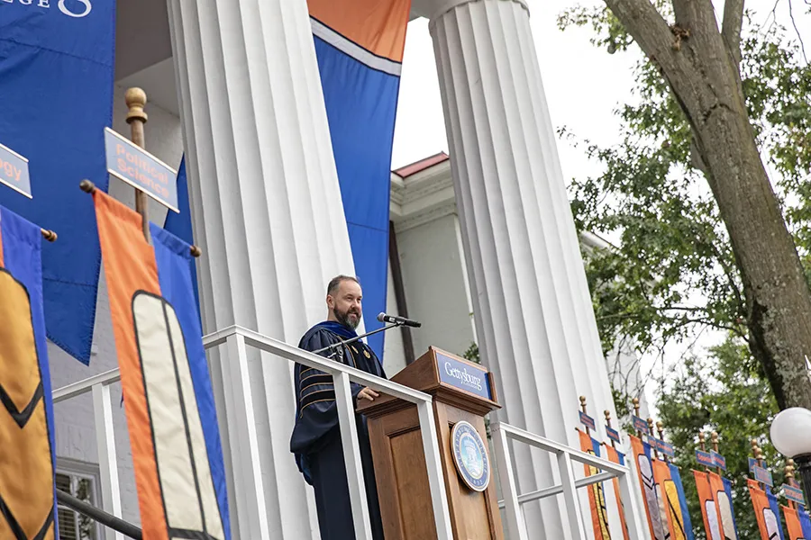 speaker at podium in Penn Hall portico