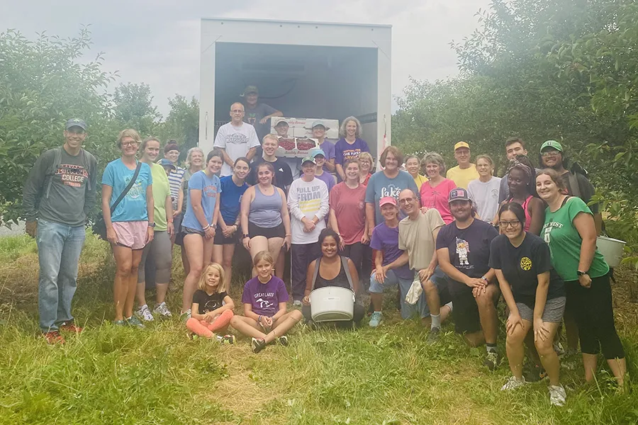 large group of students in orchard pose in front of box truck