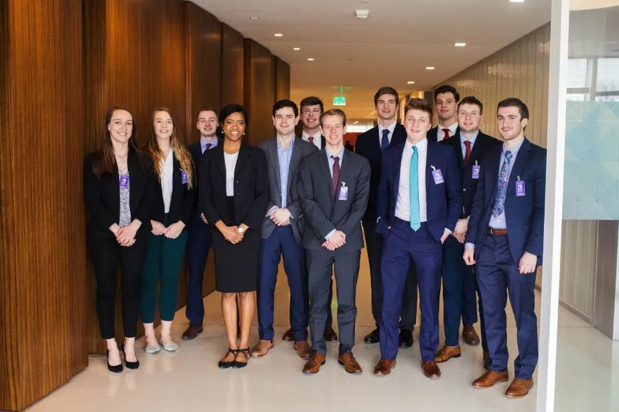 professionally dressed students pose for photo together in hallway