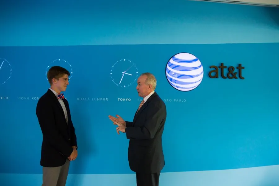 male student and alum speak together in front of blue wall with AT&T logo
