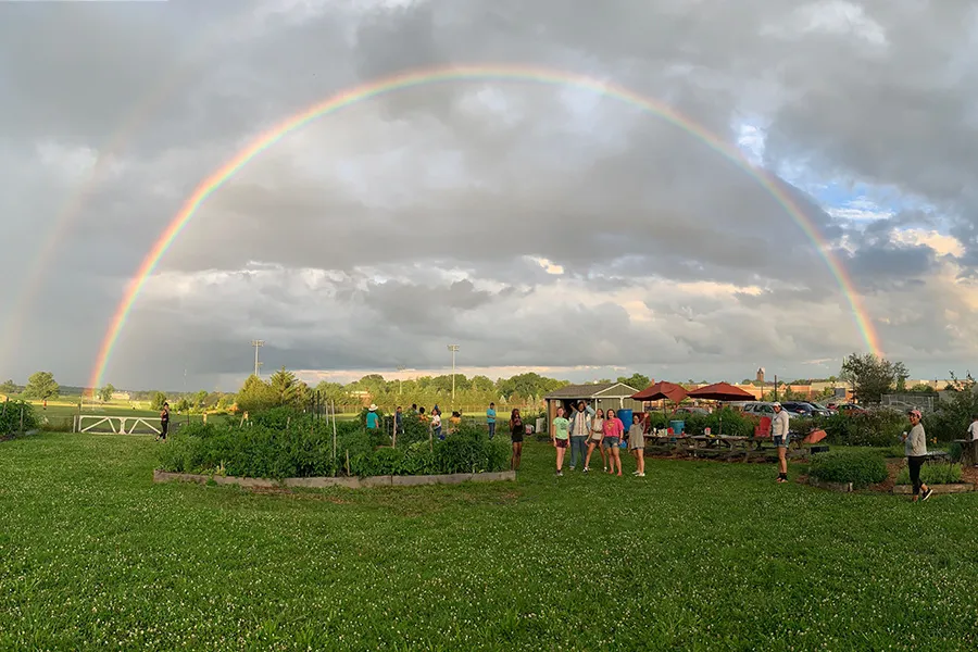 students pose under double rainbow at Painted Turtle Farm