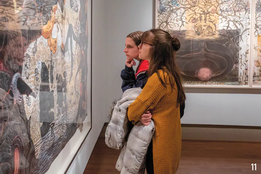 two female students ponder a piece of art in exhibit