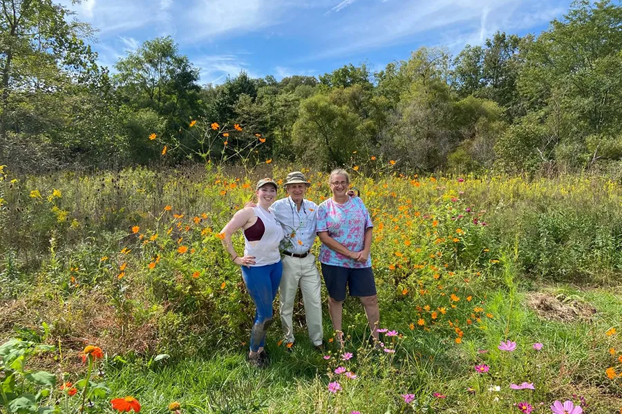 Verbrugge, Radin, and Biology Prof. Betty Ferster standing a garden