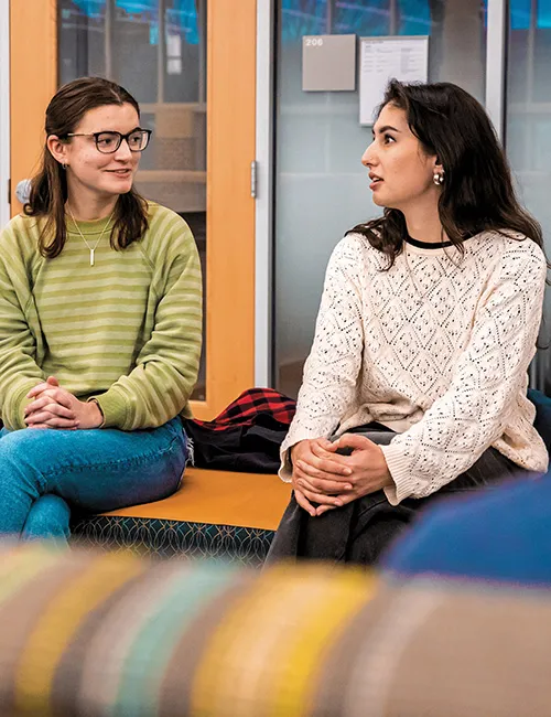 Alisha LeVine ’25 (right) talks with peers in the College Union Building.