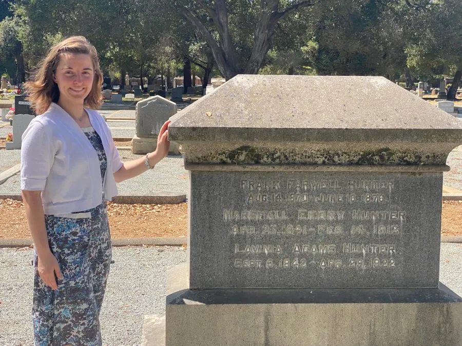 Russell stands beside a gravestone in Gavilan Hills Memorial Park.