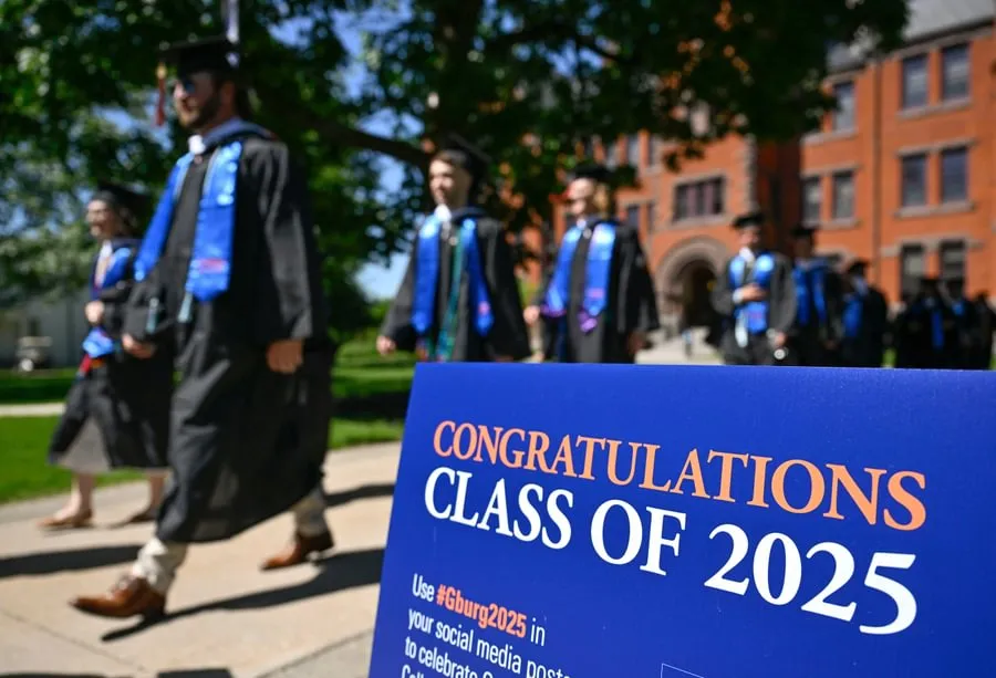 Graduates walk past Glatfelter Hall on their way to Commencement.