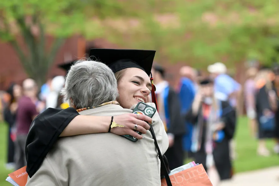 female grad hugs commencement guest