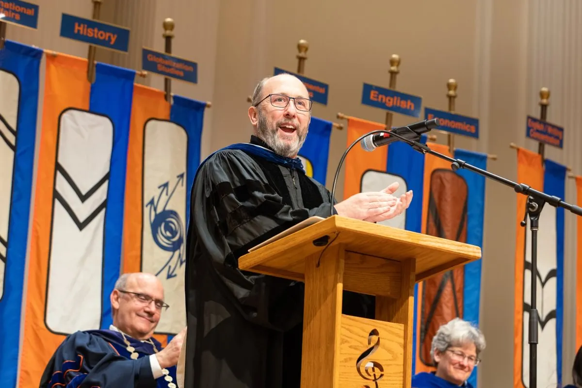 speaker at podium in front of academic program commencement banners