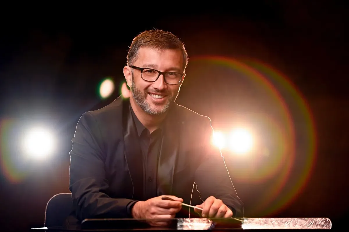 male prof smiles at camera in front of bright lights