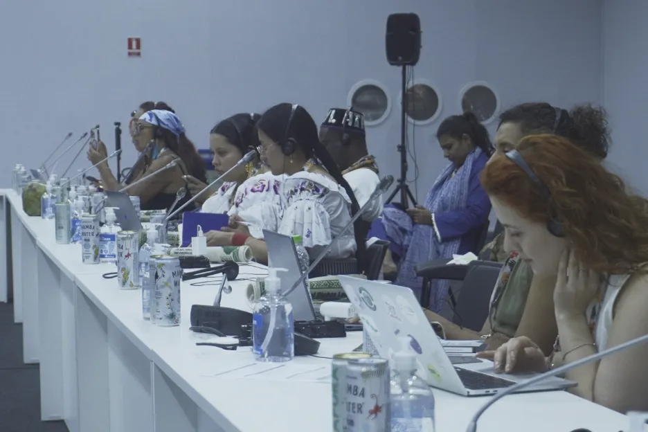 students sit at long table with microphones and laptops