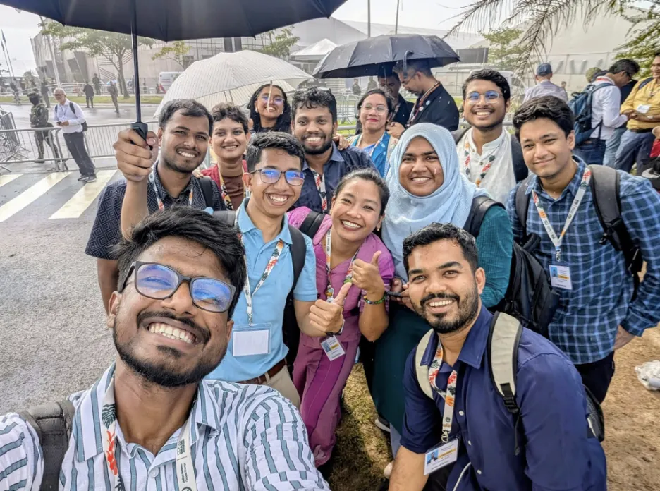 group of student smile at camera from under umbrellas outside