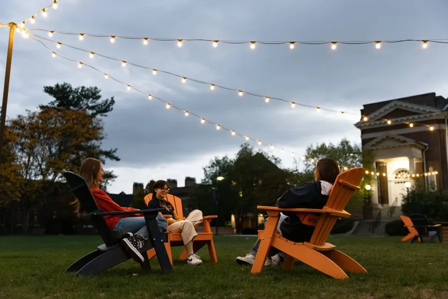 Students sitting together on Adirondack chairs outdoors
