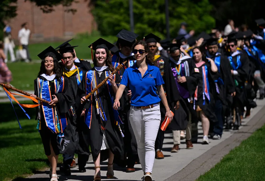 The Class of 2025 marches their way through campus prior to graduation.