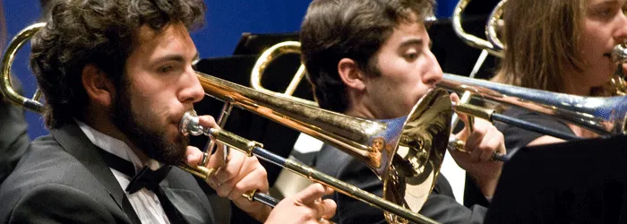 Musicians perform on trombones in an ensemble.