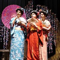 Three performers in colorful traditional Japanese attire onstage.