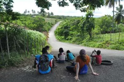 A group of students sit on a road in the Dominican Republic.