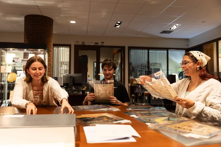 Ainsley Green ’27, Thomas Geuther ’29, and Zee Dawson ’29 explore a collection of sheet music from Special Collections.