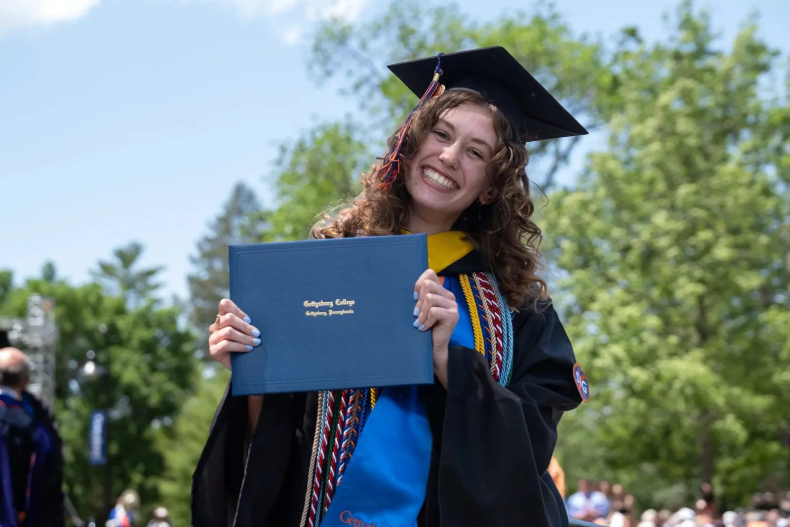 student smiling with diploma