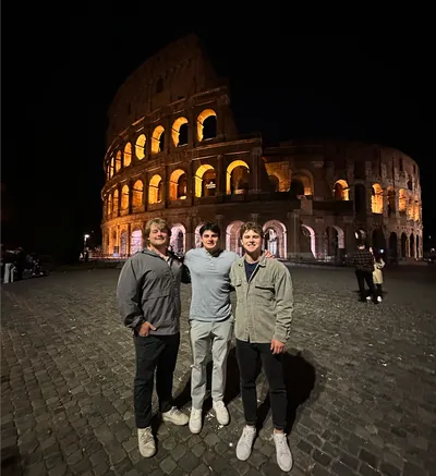 Students stand in front of Roman Colloseum at night