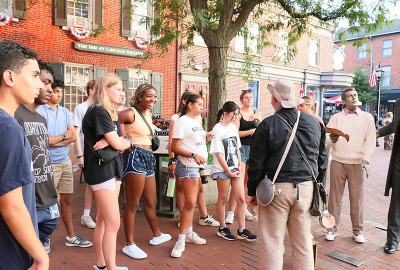 Students gather on a brick-paved street for a guided tour.