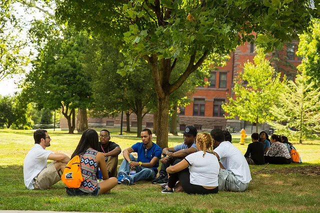 A group of people sitting on the lawn discussing