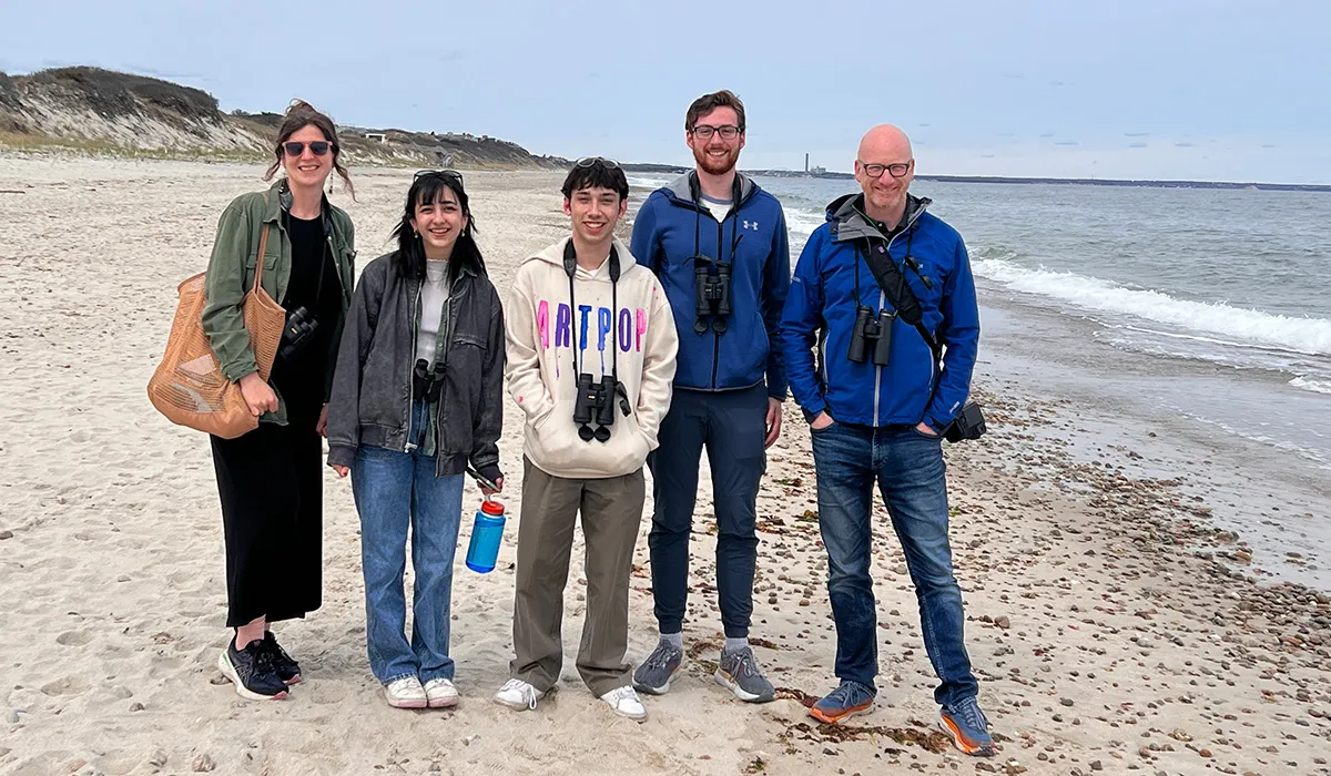A group of STEM alumni stand on a beach.
