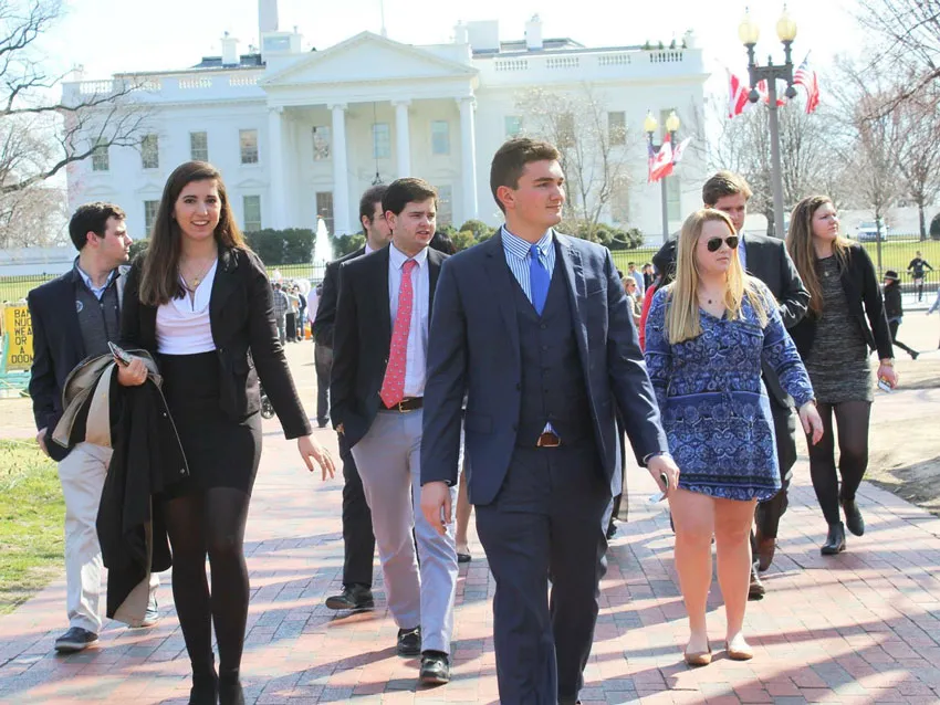 A group of students walk in front of the White House.