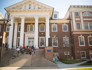 A group of students sit on stairs on campus.