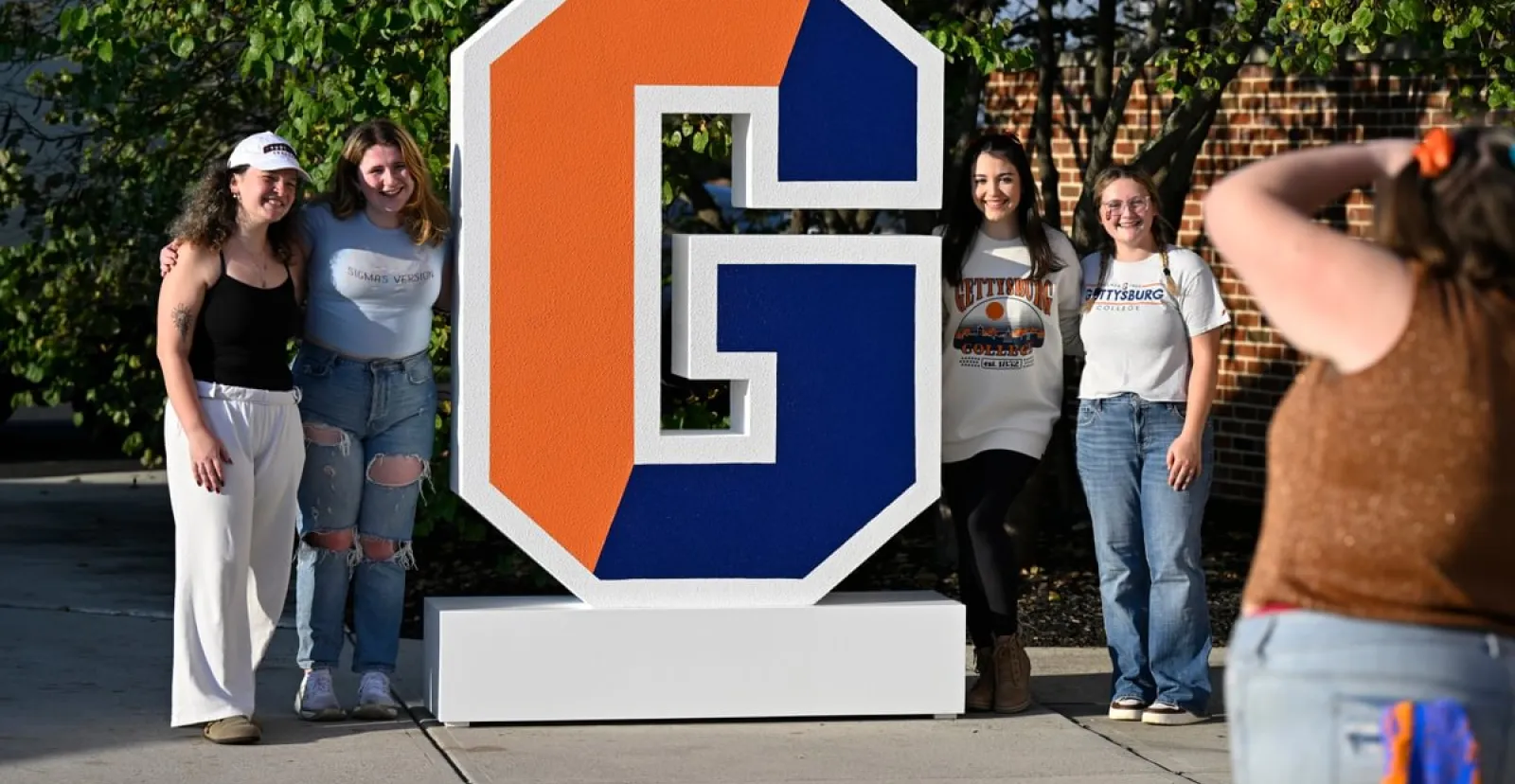 Gettysburg College students pose by the large split G outside the football stadium