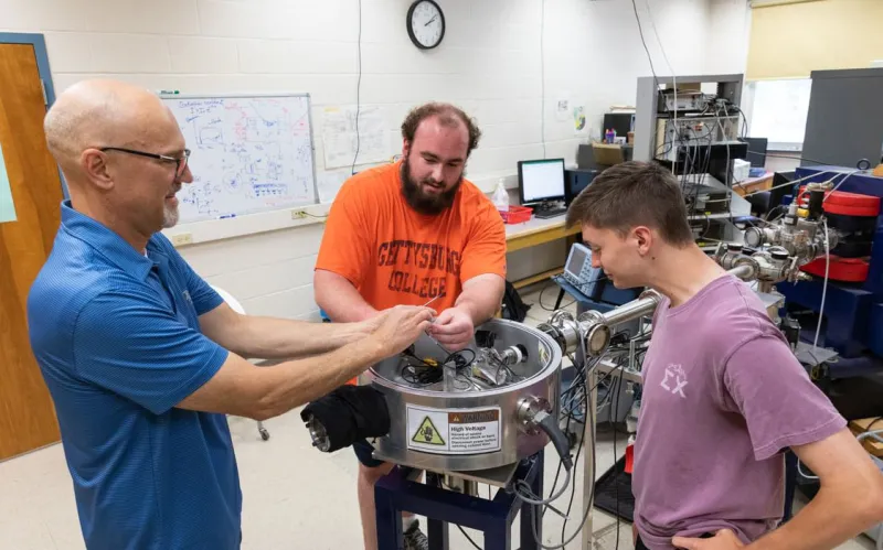 male prof and students in physics lab